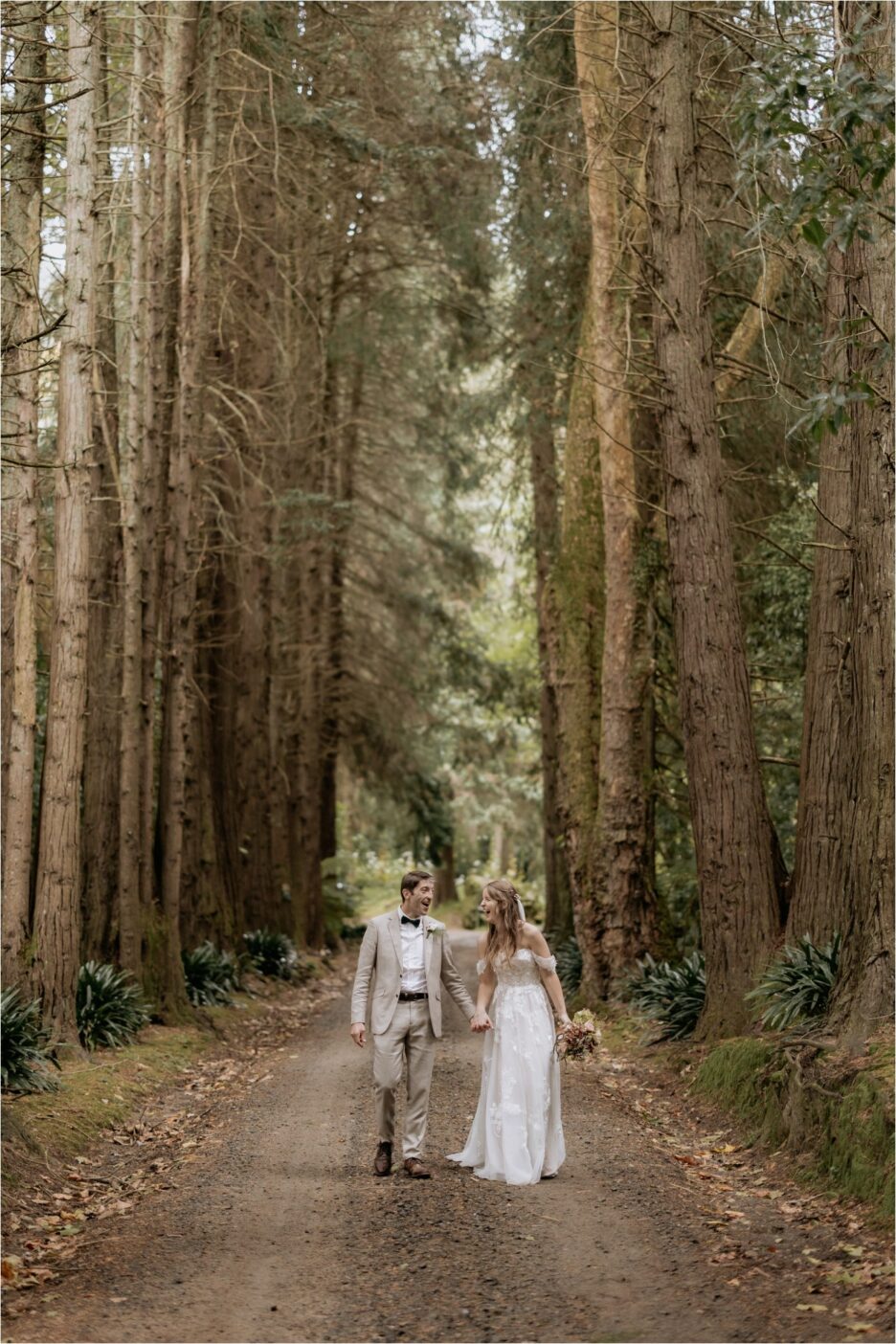 Wedding couple laughing in the red woods driveway Rotorua New Zealand