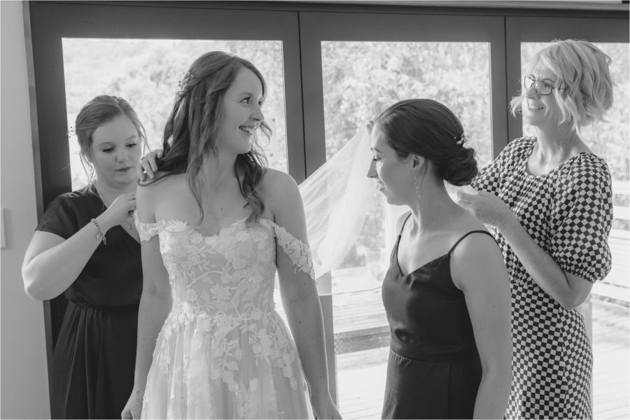 Bridesmaids and mother of bride help bride get dressed