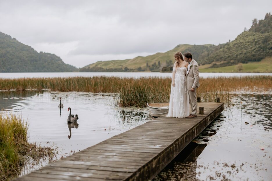 Bride and groom looking at swans arrive during photos