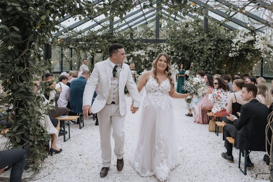 bride and groom walking down the aisle in glass house wedding