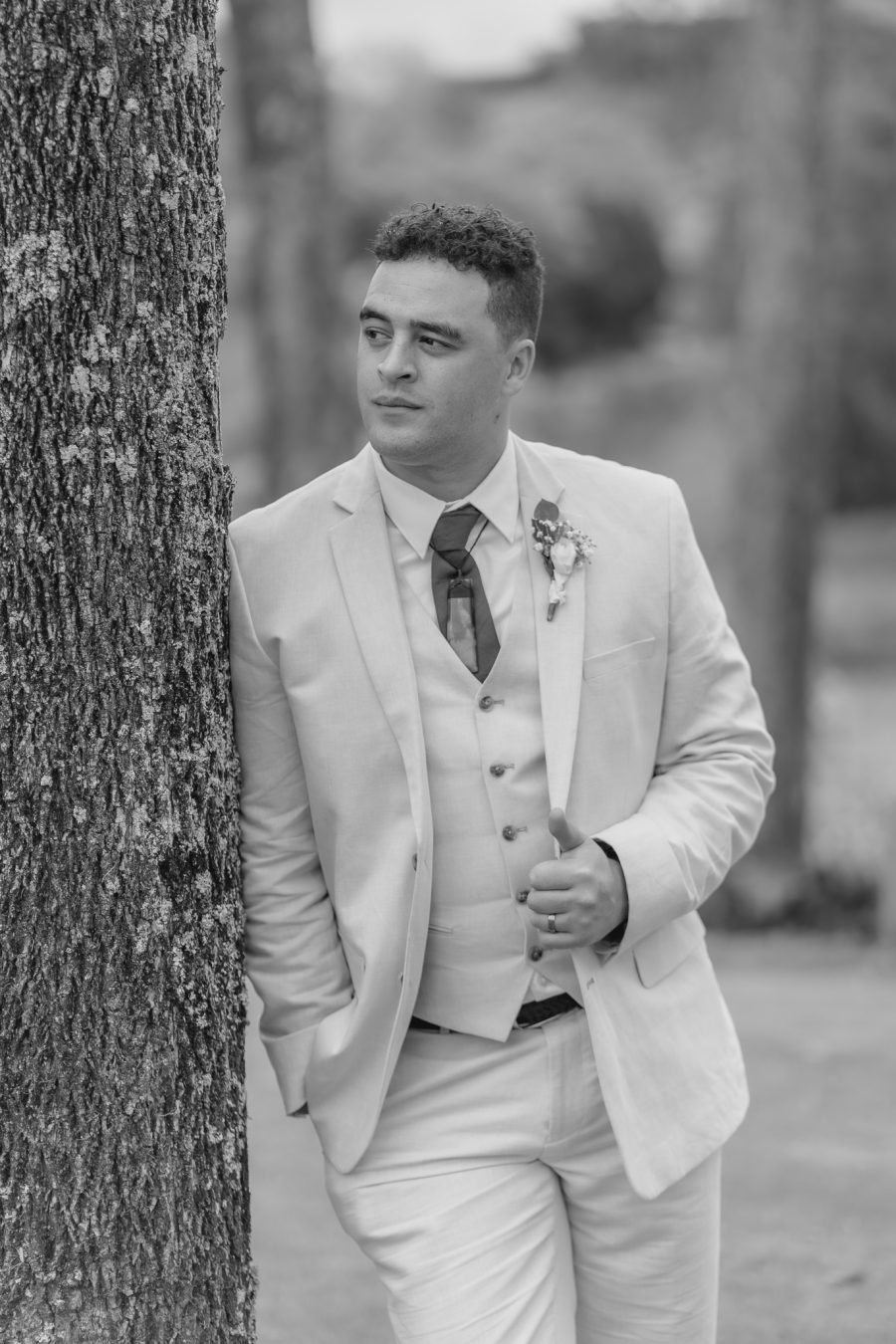 relaxed groom leaning against tree black walnut venue