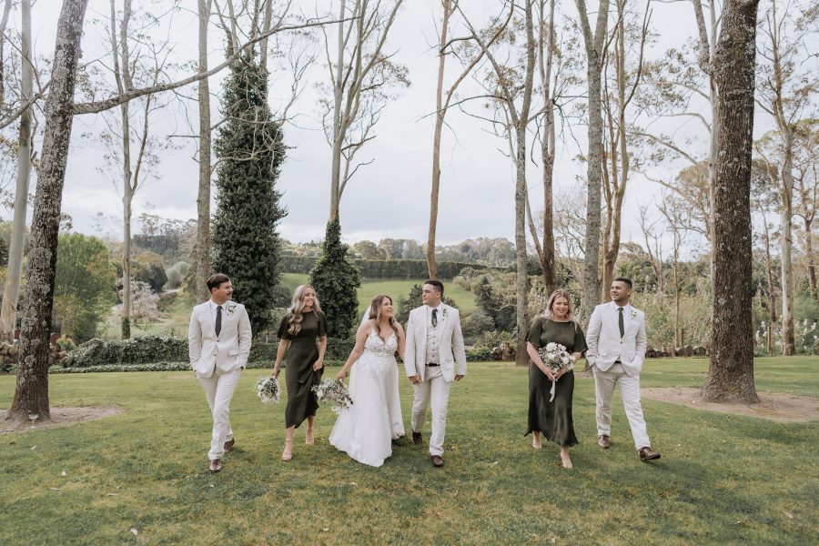 wedding party in olive green dresses and groomsmen in linen walking at black walnut
