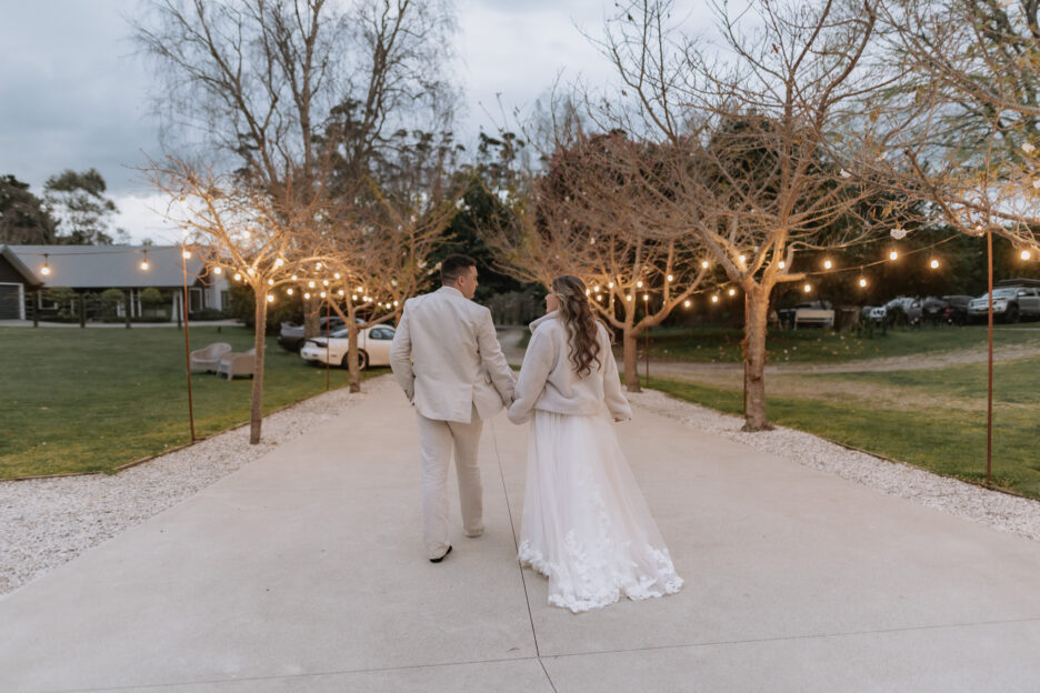 walking in the evening at black walnut driveway wedding couple fairy lights in trees