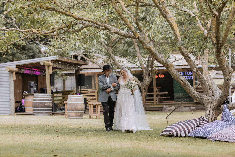 Bride walks with father of the bride down aisle at Te tumu estate