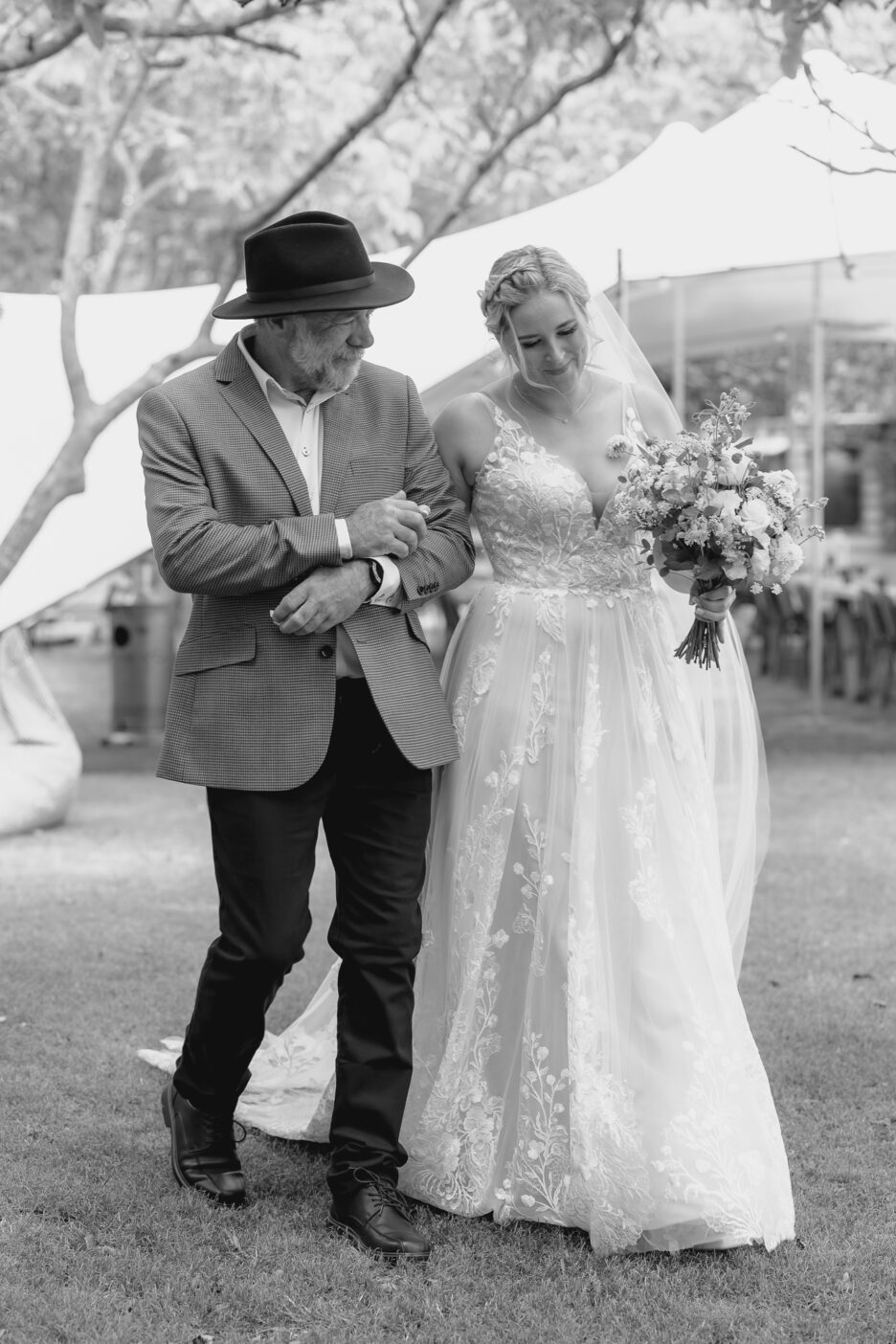 shy bride walking with father down aisle