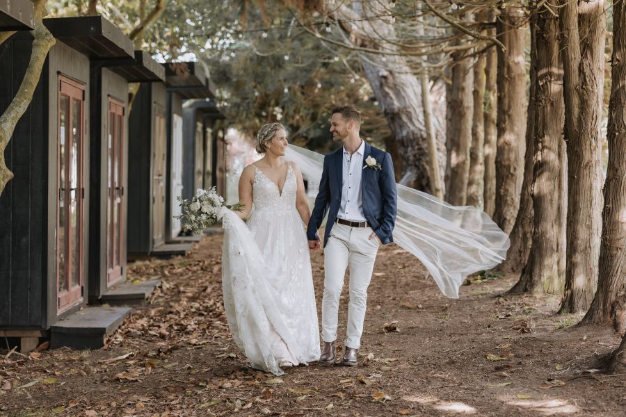 bride and groom walking down cabin accommodation lane Te Tumu estate