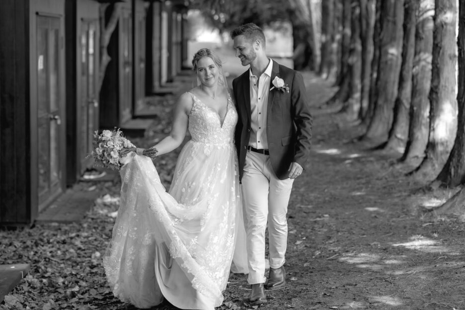 Happy bride and groom outside hut accommodation Te Tumu Estate