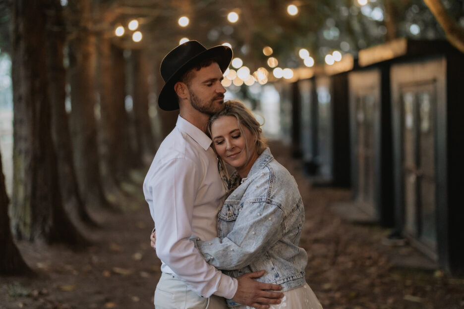 bride hugs groom at twilight with fairy lights