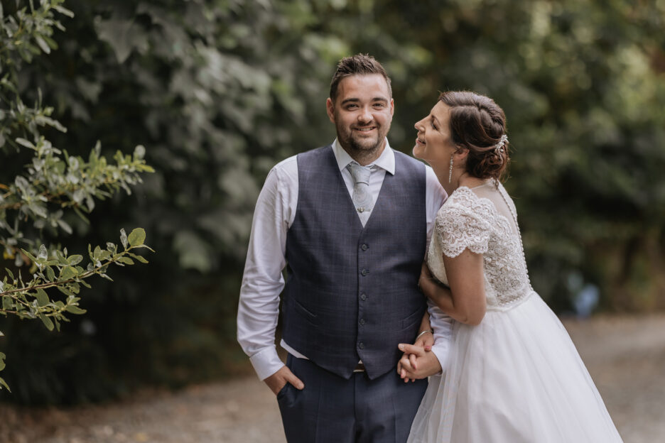 Bride looks at groom on driveway