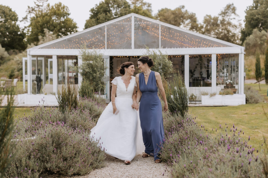 Bride and bridesmaid walking laughing in front of marquee Villa Vie NZ