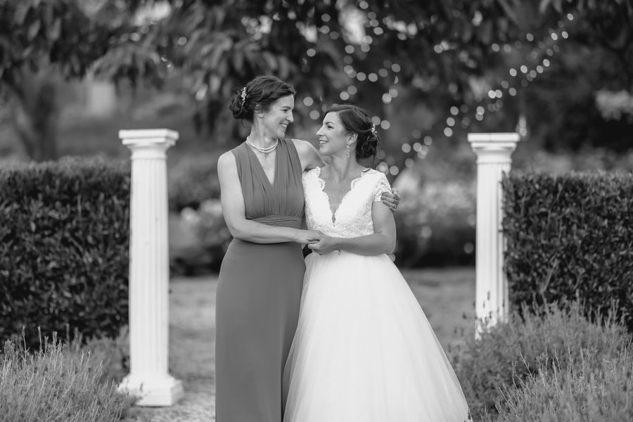 Bride and sister walking together laughing in Villa Vie gardens