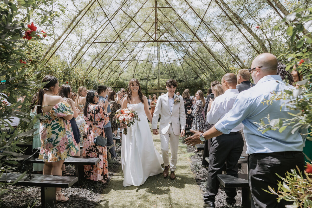 bride and groom walk aisle happy