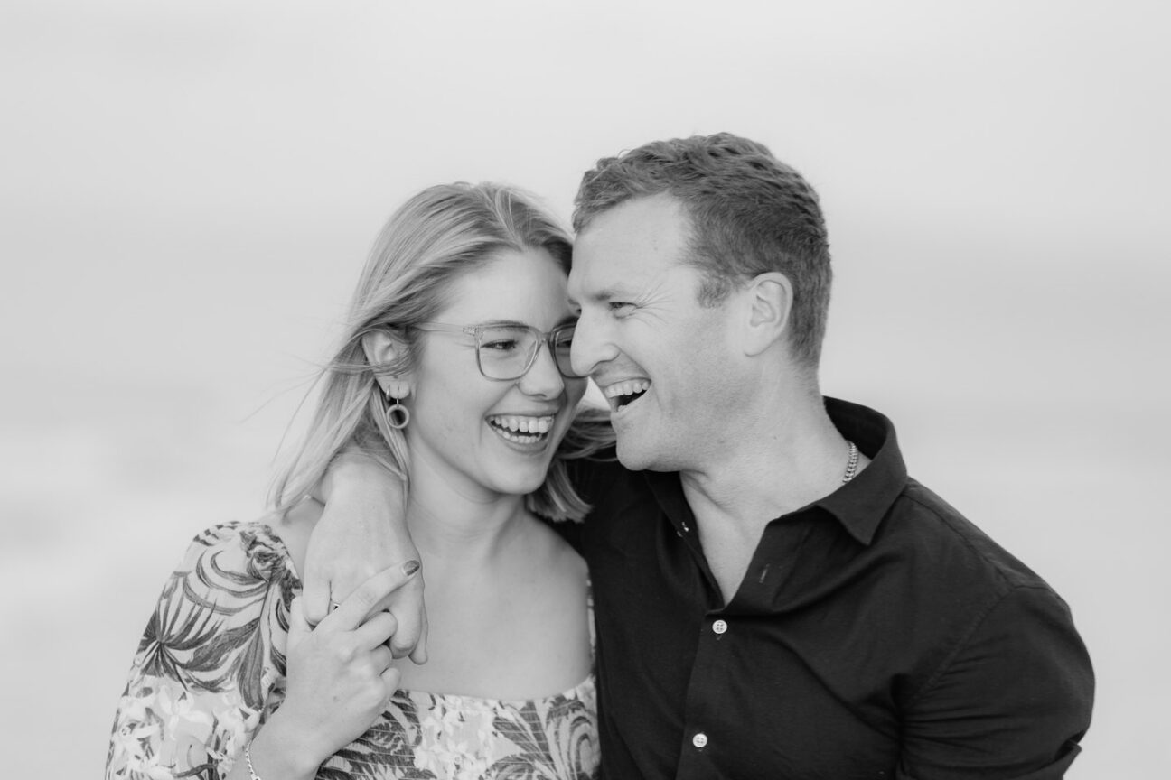 girl laughs at her fiance black and white candid photo during engagement shoot on Papamoa Beach by Tauranga wedding photographer pure images Photography