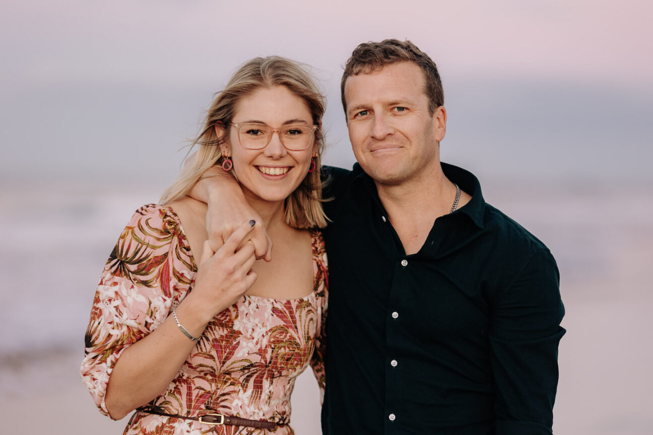 Happy engaged couple looking at camera during beach engagement shoot