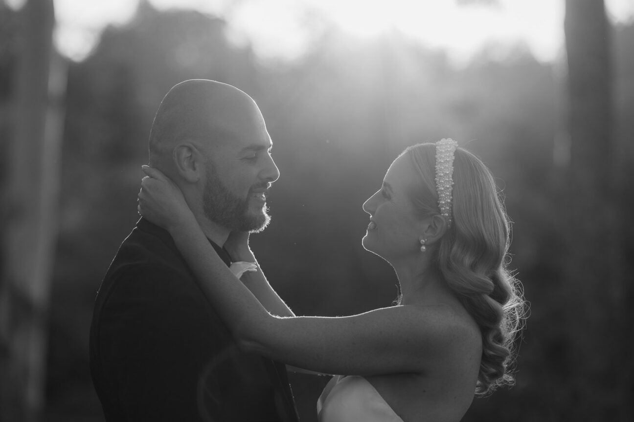 black and white image of bride holding her hands around her grooms neck
