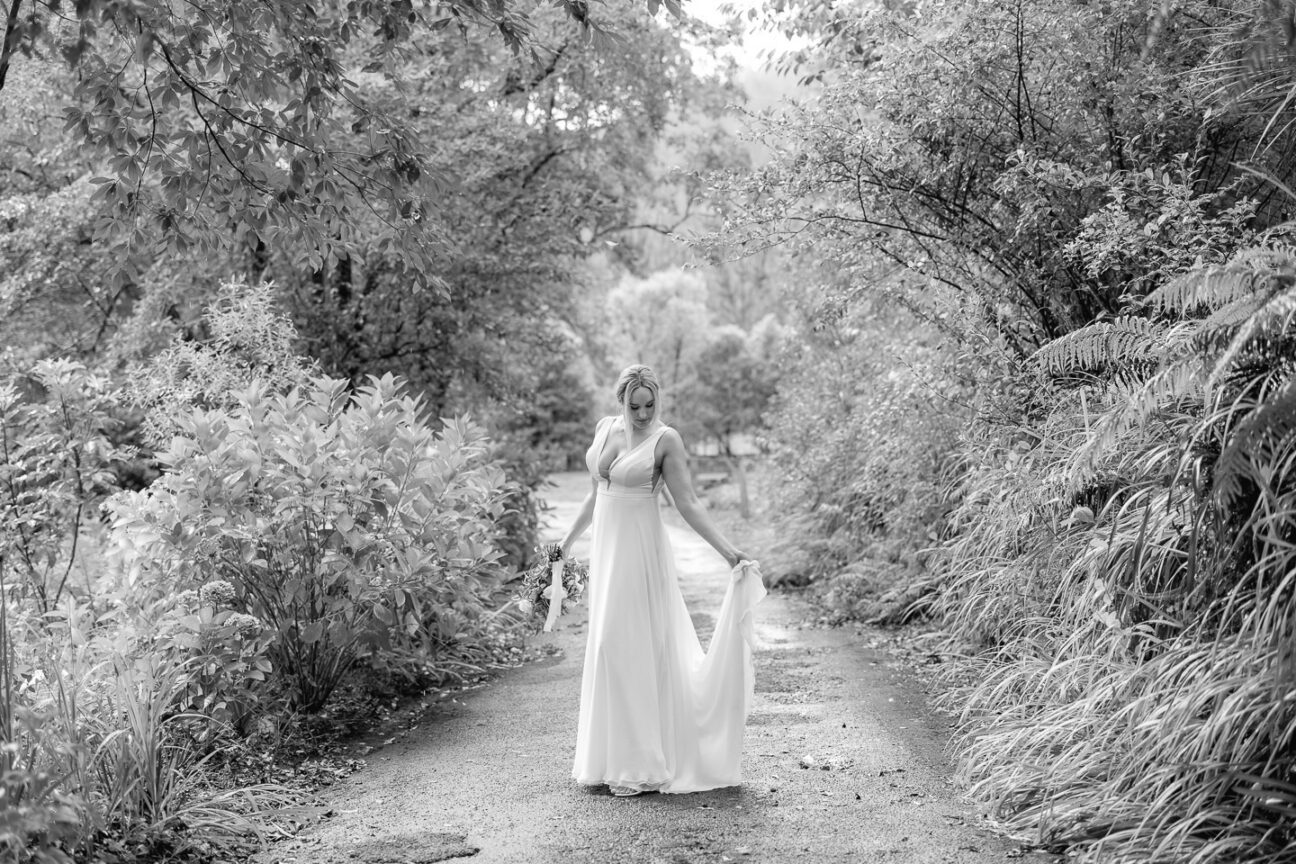 bride holding her train in contemplative moment on driveway