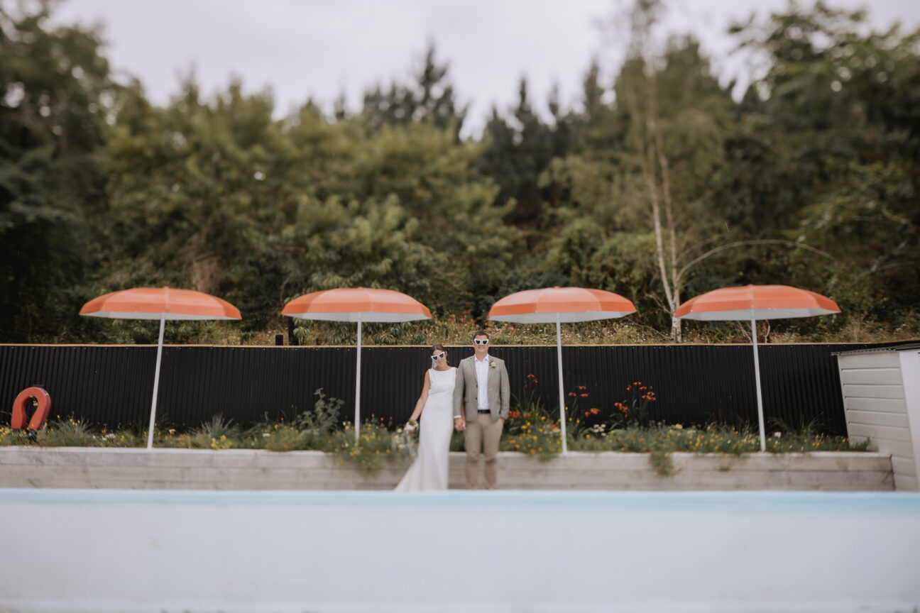 vintage photo of bride and groom swimming pool with orange umbrellas