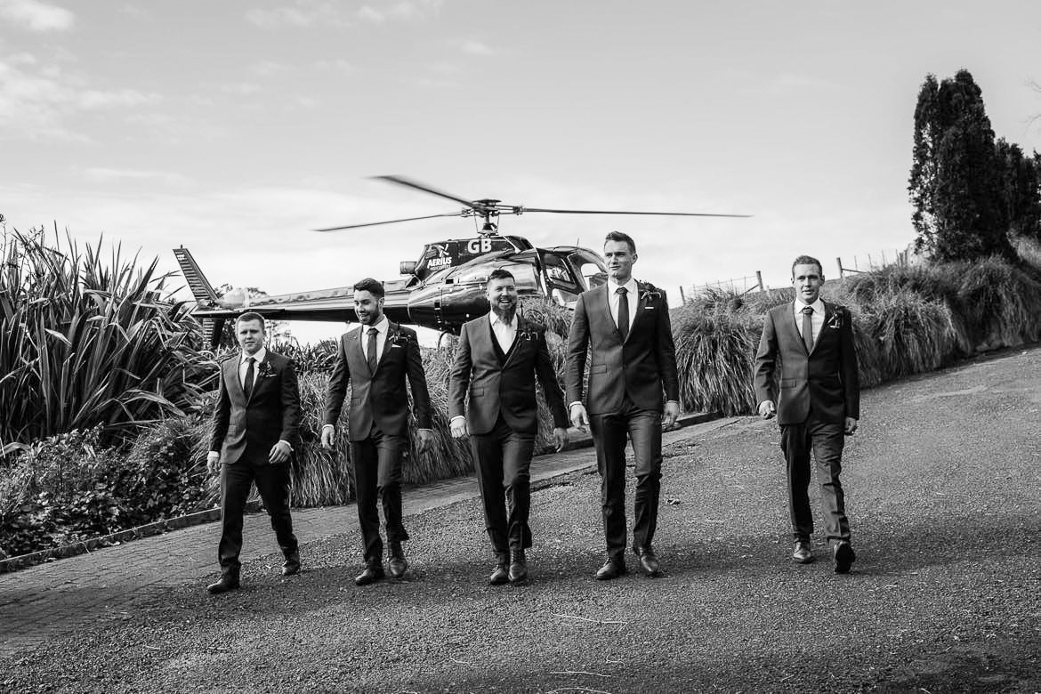Groomsmen walk in front of helicoper
