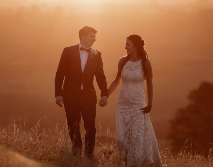 Bride and groom walking on hills at sunset