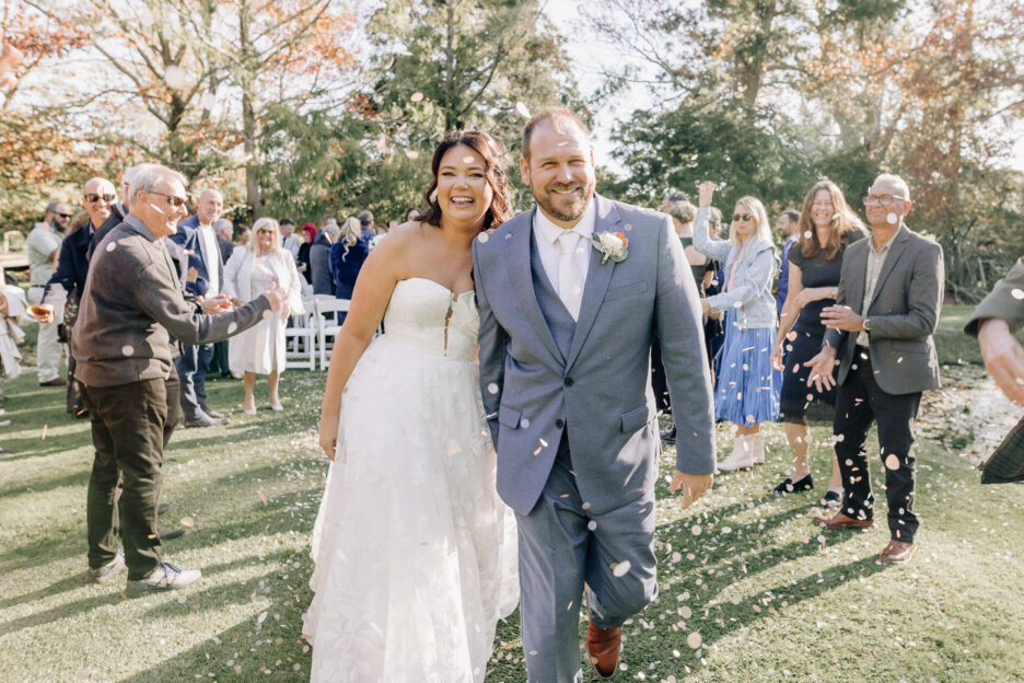 happy bride and groom walking under confetti just married