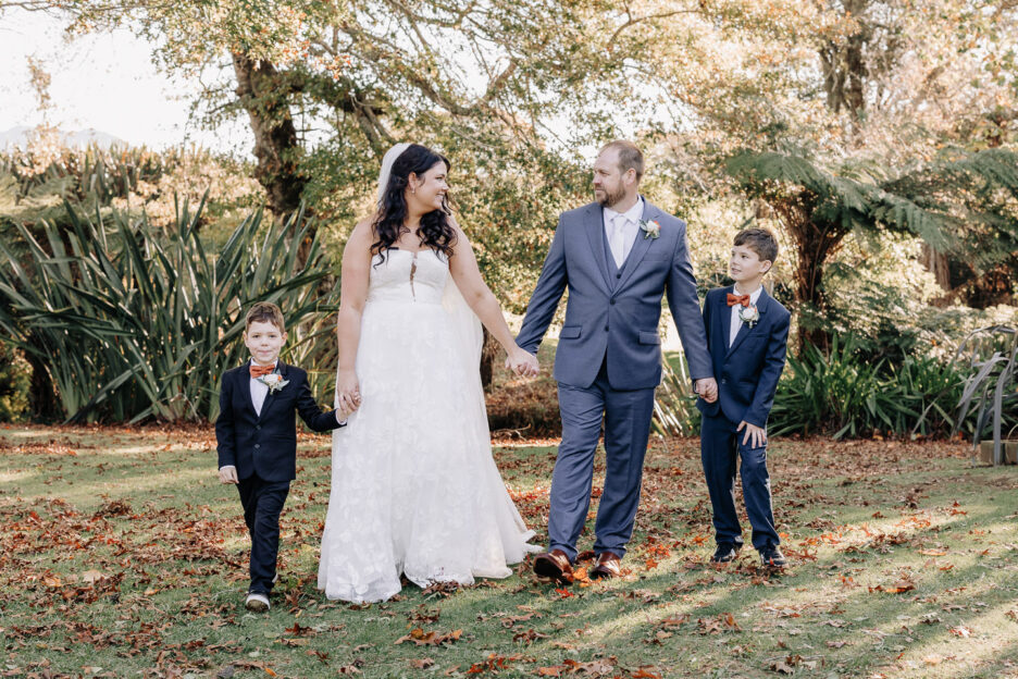 bride and groom walking with children happy family waihi wedding garden venue