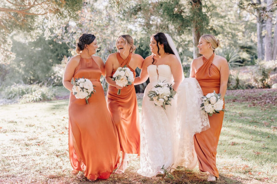 fun girls laughing walking with bride in orange dresses