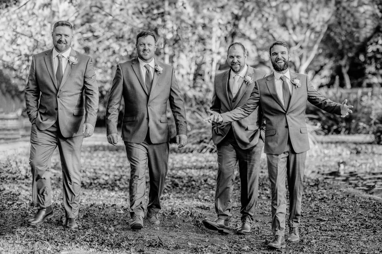 happy relaxed groomsmen walking laughing black and white photo