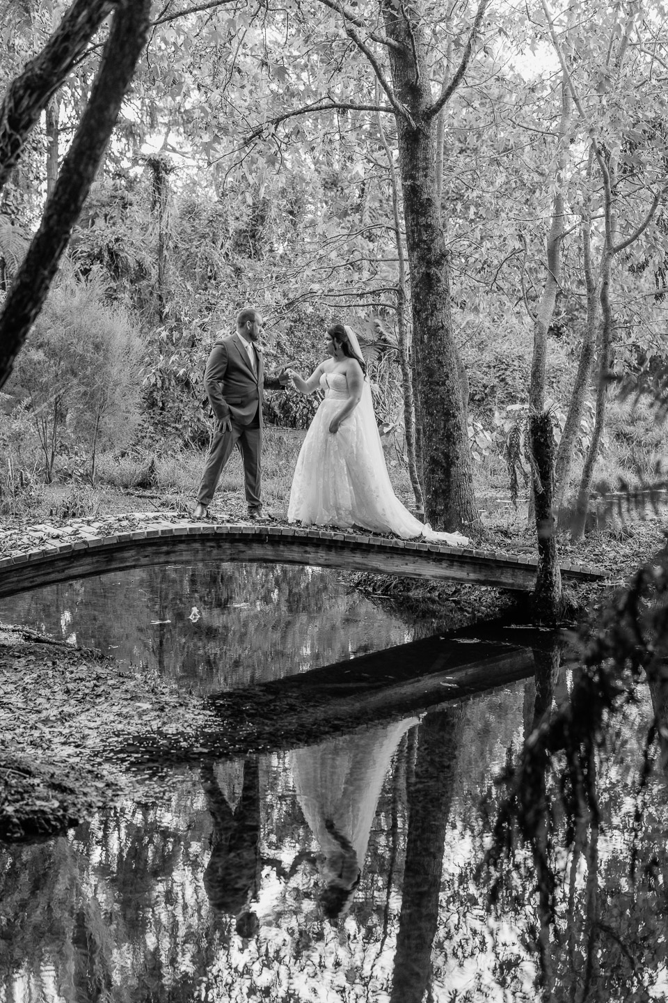 bride and groom walking bridge over pond waterlily gardens waihi New zealand