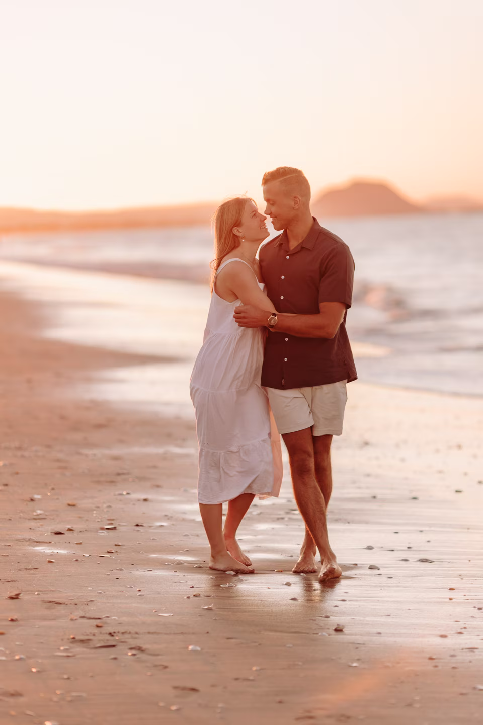 couple playfully walking papamoa beach engagement shoot
