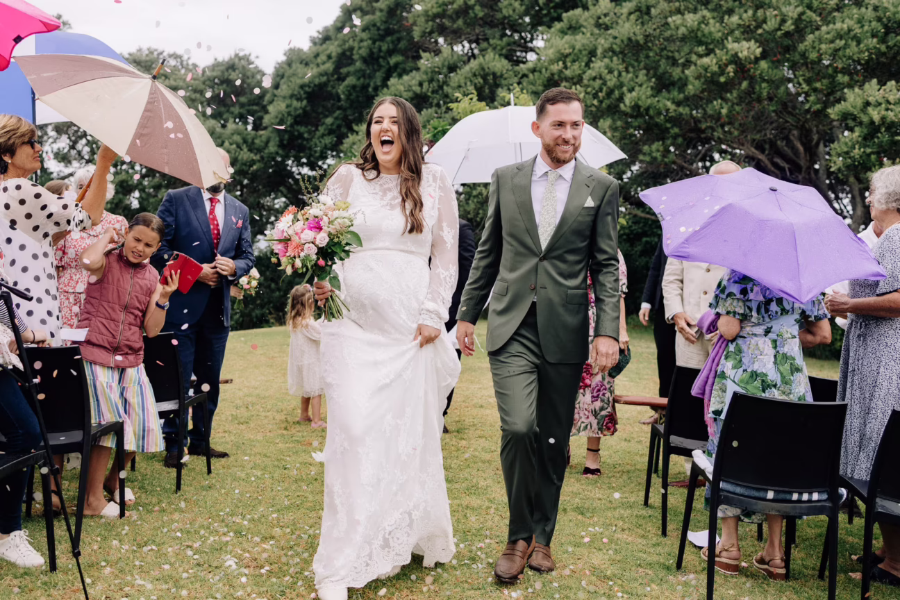 Happy bride and groom walk down the aisle in the rain