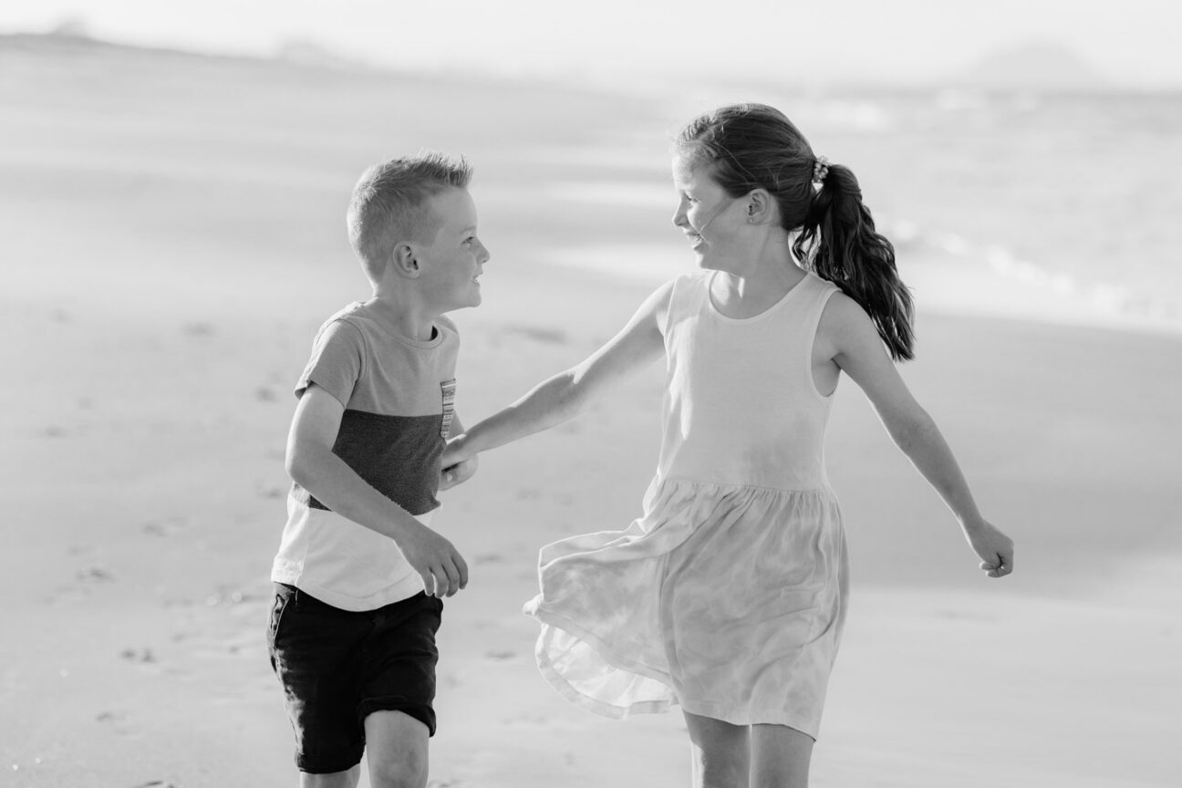 brother and sister together running on beach