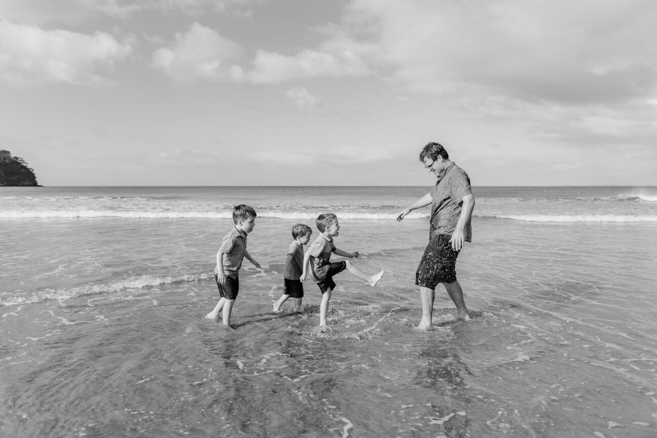 dad playing with 3 boys splashing water